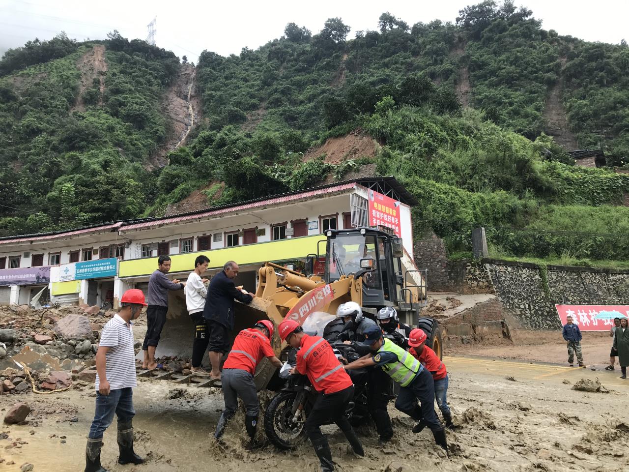 8月18日，搶險(xiǎn)人員與民警幫助被困群眾的摩托車通過涉水路面.jpg